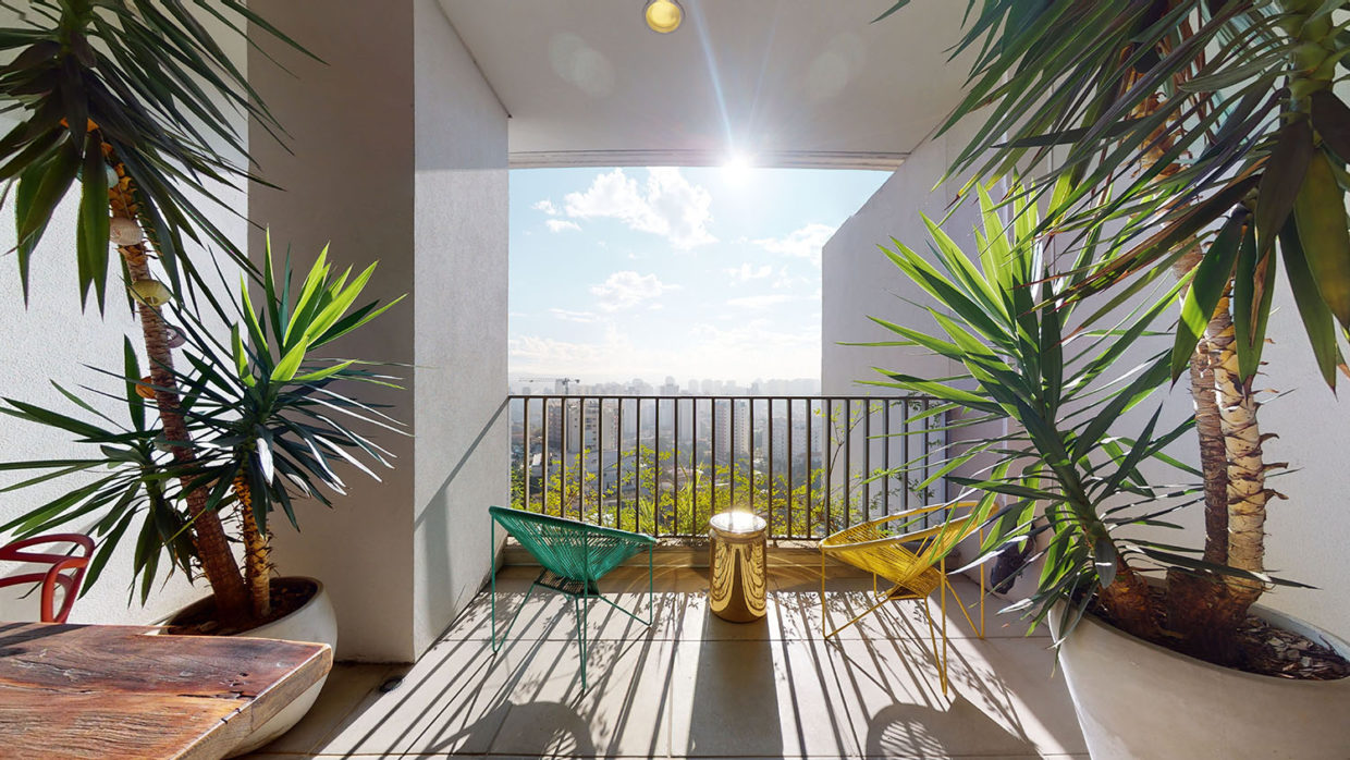 Foto de varanda com plantas, duas cadeiras, uma bela vista da cidade e o sol brilhando forte